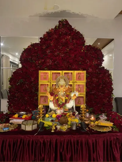 A truly magnificent and devotional setup, this backdrop is shaped like a temple or throne and constructed from thousands of red roses.