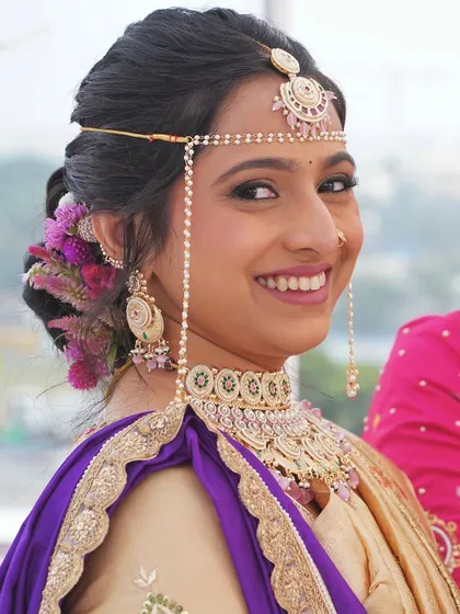 This bride's side profile highlights her beautiful hair bun adorned with fresh flowers and the traditional Maharashtrian mundavalya.