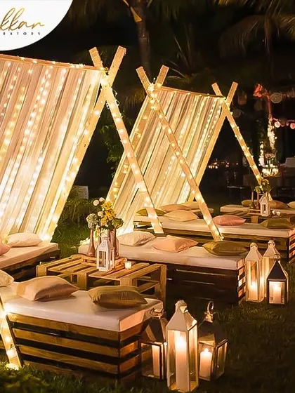 A beautiful garden-side decor setup for a Mehendi night. The tent-style seating with fairy lights and lanterns creates a cozy and magical atmosphere for an outdoor event.