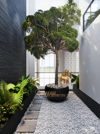 A tranquil indoor courtyard with a central tree, white pebbles, and stepping stones, creating a peaceful zen garden within the home.