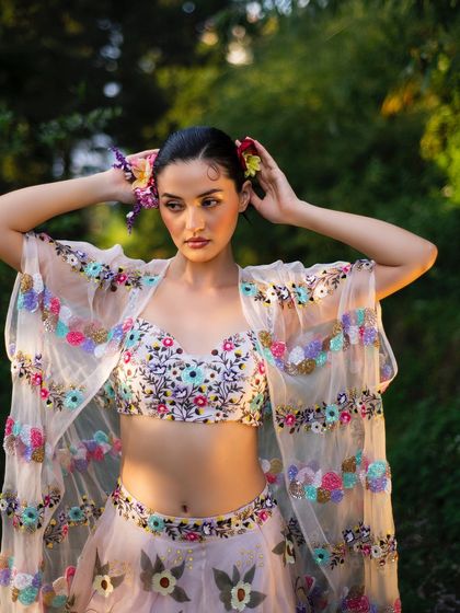 A close-up of the model arranging flowers in her hair, a perfect detail shot for Baavli's nature-inspired collection.