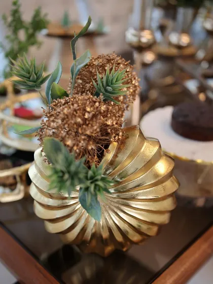 Our sculptural golden vase with a swirl design, holding a small floral arrangement. This piece is more than a vase; it’s a work of art, designed to be a stunning centerpiece on any table.