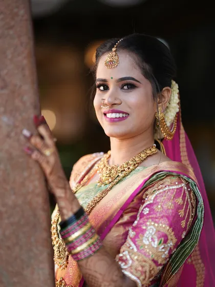 A beautiful, smiling portrait of a South Indian bride. The soft, natural lighting highlights her features and the exquisite detail of her wedding jewelry.