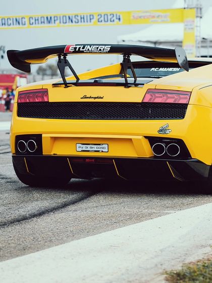 The rear of a yellow Lamborghini Gallardo, showcasing its massive spoiler and aggressive diffuser. This is a machine built for downforce and speed.