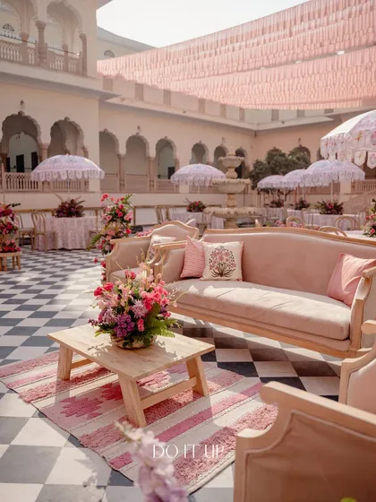 An elegant lounge area at the Jaipur welcome lunch. A classic sofa is paired with a rustic wooden table and a pink patterned rug, creating a comfortable and stylish space for guests to relax.