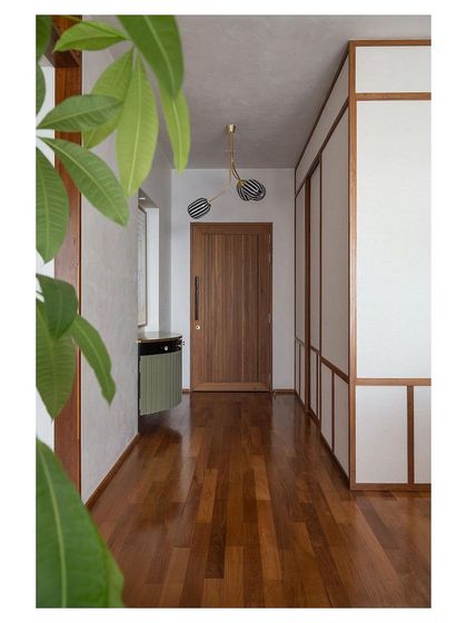 The entrance corridor, with its warm teak flooring and paneled walls, sets a calm and welcoming tone for the entire home.