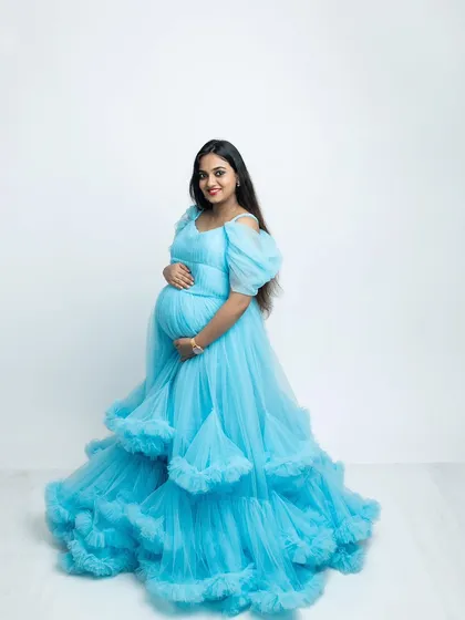 A full-length solo portrait of the mother-to-be in a vibrant blue gown. Her happy smile and confident pose make for a stunning and memorable maternity photograph.