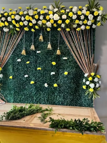 A sneak peek at a setup in progress. This design combines a green wall with traditional yellow flowers and brass bells for a classic festive look.