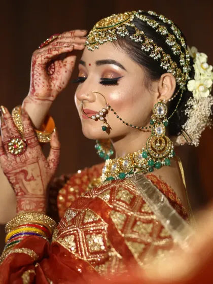 An artistic pose showing off the side profile, the intricate hairstyle with a sheeshpatti, and the glowing highlighter on the cheekbones.