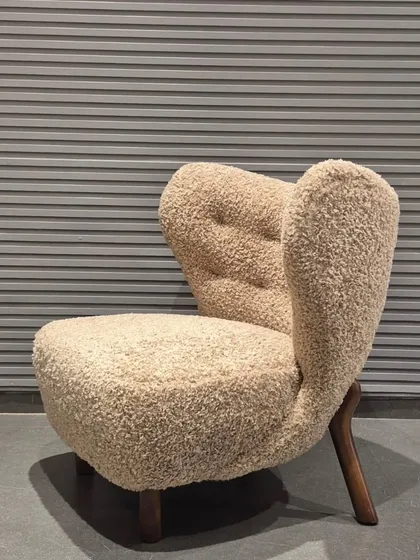This is one of my favourite designs, a lounge chair upholstered in a beautiful bouclé fabric. The unique, sculptural form and solid wood legs make it a true statement piece for any living room or building lobby.