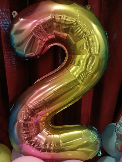 A large, iridescent number '2' foil balloon, perfect for marking a second birthday.
