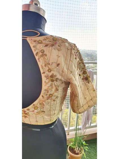 A beautifully detailed beige blouse with floral embroidery and beadwork, perfect for a sophisticated and understated look.