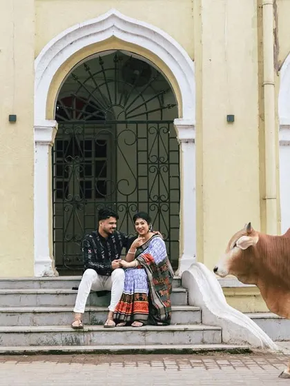 A candid, unscripted moment that makes hometown shoots so special. As the couple sat on the steps of a historic building in Sambalpur, a local resident, a cow, casually walked past, adding a touch of authentic, everyday life to their portrait.