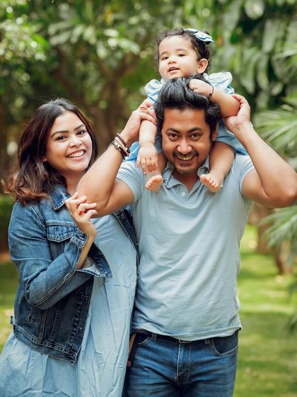 An adorable outdoor family portrait with their daughter enjoying a shoulder ride. The genuine smiles and natural setting make this photo feel so alive.
