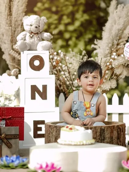 A picture-perfect first birthday setup. This little boy is surrounded by teddy bears, presents, and his birthday cake, ready to celebrate his big day.