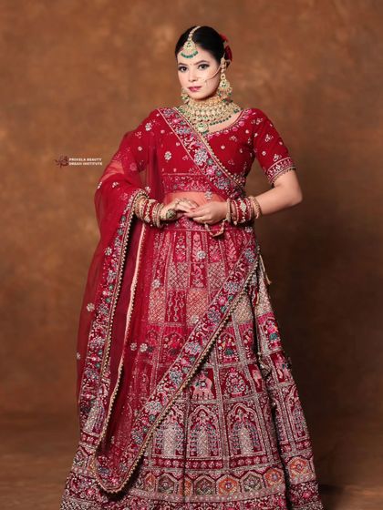 A full view of the bride's stunning red lehenga. The classic bun hairstyle is the perfect choice to balance the grandeur of the outfit and jewelry.