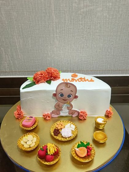 A unique cake celebrating a baby's "Annaprashan" or first solid food ceremony. The design features miniature edible versions of traditional foods served during the ritual.