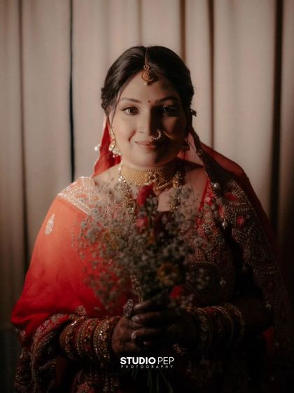 A warm, intimate portrait of the bride, Shalini, holding a bouquet of flowers, her smile genuine and full of joy.