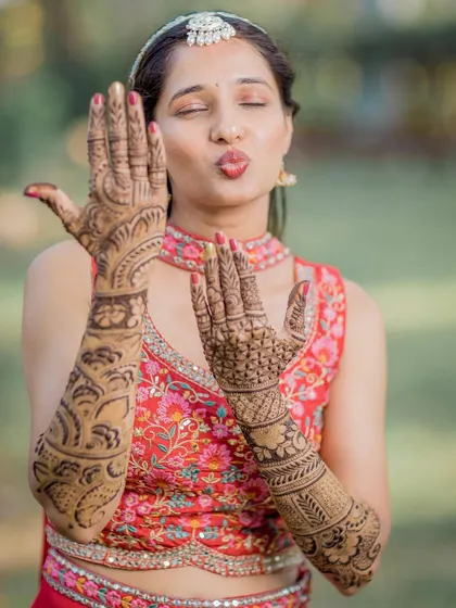 A playful bride shows off her elaborate Mehendi design, a beautiful and essential part of the pre-wedding preparations.