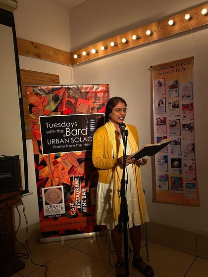 A performer shares her poetry, her expression lit by the warm stage lights. Every Tuesday, our cafe transforms into a sanctuary for words.
