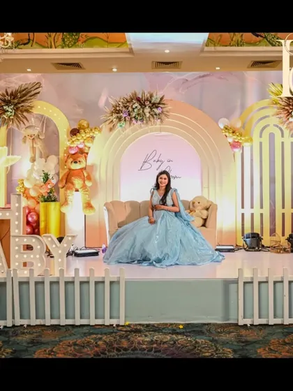 The mom-to-be enjoying the beautiful stage we created for her baby shower. The soft pastel colors of the decor and her gown create a picture-perfect moment against the "Baby in Bloom" backdrop.