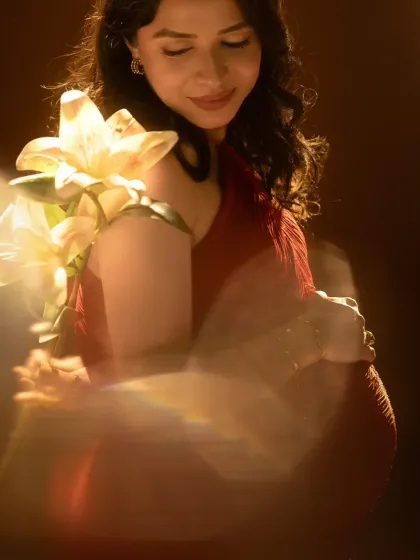 An artistic and dreamy portrait. We used a special lens effect to create a soft, ethereal glow, with the lily on her shoulder adding a touch of natural beauty to this studio shot.