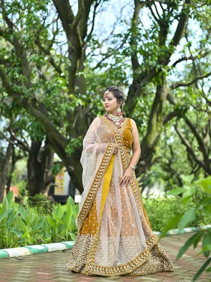 A side-profile shot of the mustard yellow lehenga, highlighting the contrast between the yellow skirt and the sheer dupatta.