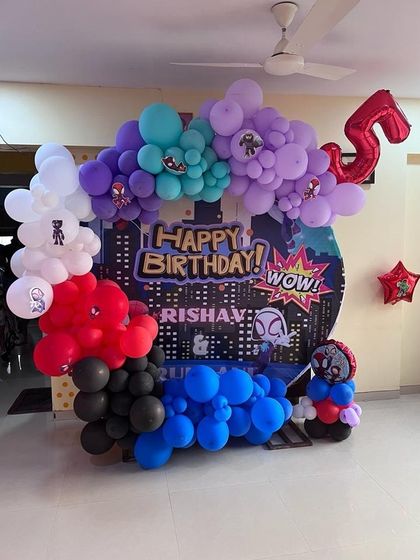 A super celebration for a 5th birthday with this action-packed Spiderman theme. The backdrop features a cityscape with 'WOW!' comic book art, surrounded by a multi-colored balloon arrangement and Spiderman character balloons.