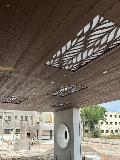 Don't neglect the fifth wall. Here, we've used wooden-finish metal panels for a maintenance-free ceiling, integrated with backlit CNC-cut jali panels in a leaf pattern. This adds a layer of sophistication and ambient lighting to an outdoor portico.