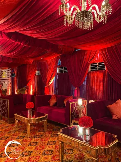 I created this luxurious lounge area with plush red velvet sofas, gold-accented tables, and a ceiling of draped red fabric, providing a comfortable and stylish space for guests to relax.