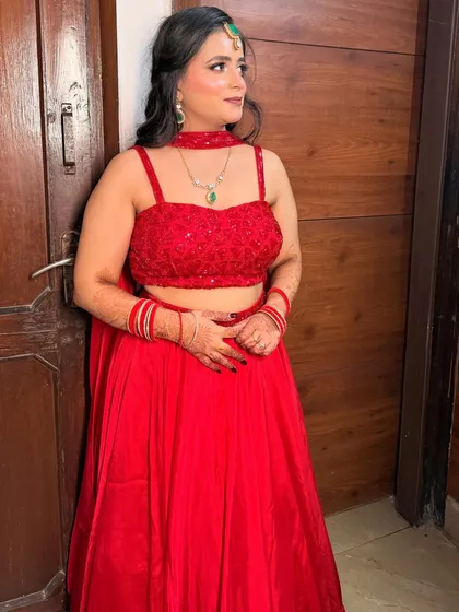 The full view of the red lehenga party look. The half-up hairstyle and radiant makeup create a beautiful and festive style.