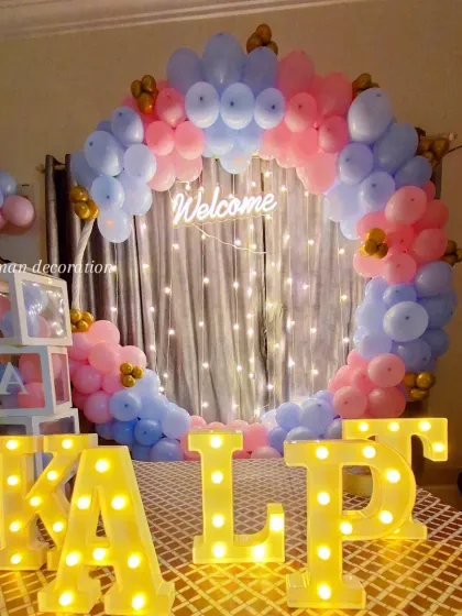 A 'Welcome Home' party for a newborn. This features a pink and blue balloon ring, a 'Welcome' neon sign, 'BABY' blocks, and the baby's name in marquee letters.