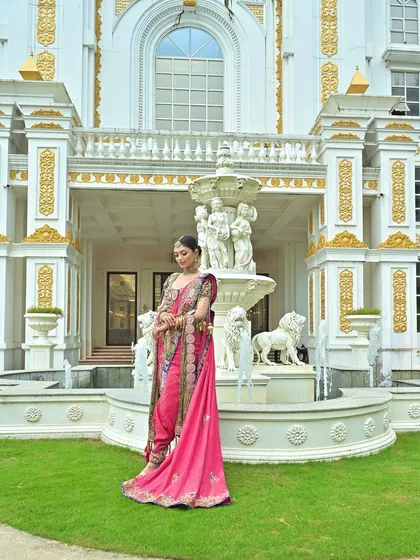 A full-length view of a modern Maharashtrian bride in a pink Nauvari, set against a grand, royal backdrop.