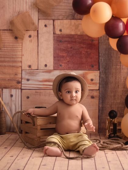 This little cowboy is taking a rest, sitting with his rope and hat in our rustic, western-themed setup.