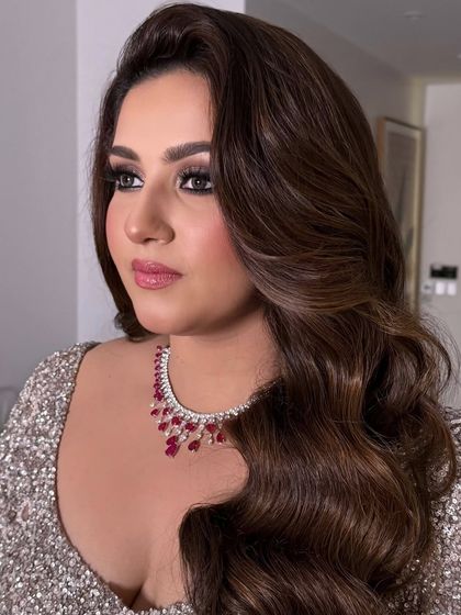 A close-up of a bride with beautiful side-swept waves and dramatic eye makeup, a classic glam look.
