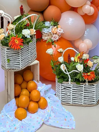 Baskets of fresh oranges and floral arrangements add to the rustic charm of this citrus themed decor. The combination of natural fruit, flowers, and woven baskets creates a wholesome and inviting atmosphere.