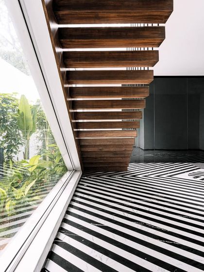 Another view of the Tellado staircase, emphasizing its lightness and the way it interacts with the graphic black-and-white marble floor. The design is a careful balance of material, form, and transparency.