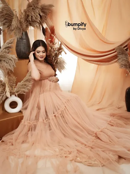 Our pampas grass and draped fabric setup creates a soft and dreamy atmosphere. The mom-to-be looks radiant in a peach gown, surrounded by warm, earthy textures.