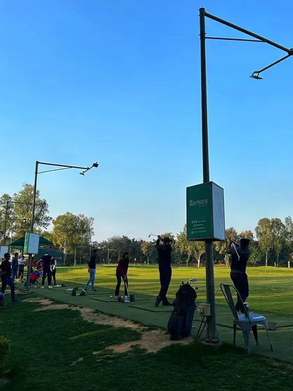 A line of golfers practices under the clear blue sky, a perfect day for being on the range.