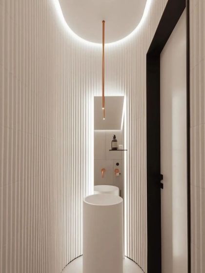 Even a small space like a powder room deserves a 'wow' moment. This toilet design uses curved, fluted walls, a sleek pedestal sink, and dramatic cove lighting to create a modern and sculptural look.