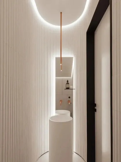 Even a small space like a powder room deserves a 'wow' moment. This toilet design uses curved, fluted walls, a sleek pedestal sink, and dramatic cove lighting to create a modern and sculptural look.