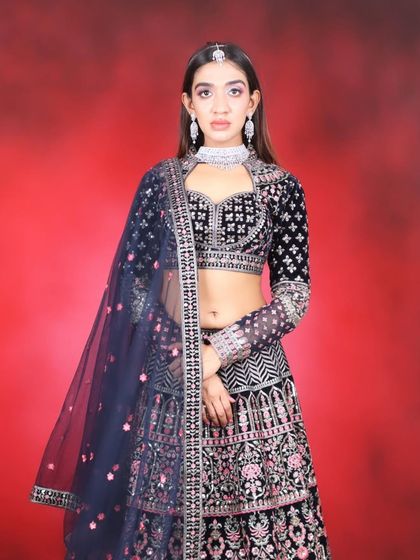 A stunning reception or cocktail party look featuring a navy blue velvet lehenga. The makeup is sharp and modern with a pop of pink on the eyes.