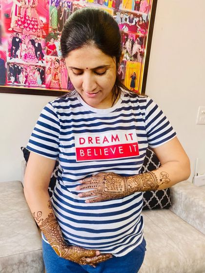 A happy mom-to-be cherishing her baby bump and her beautiful, intricate maternity mehndi. The design is a celebration of this special time in her life.
