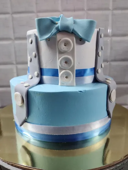 A "little man" themed two-tier cake. This adorable design features a shirt with a bow tie and suspenders, perfect for a first birthday.