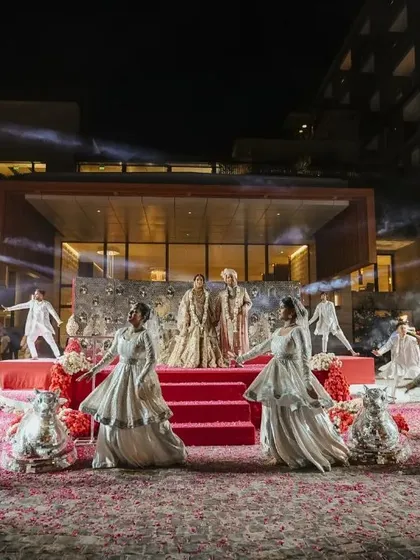 A wide shot of the groom's grand entrance, with dancers performing on a red carpet, showcasing the opulence of the event.