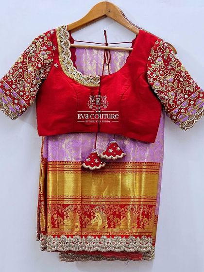 A Kanchi pattu saree with a heavy maggam work blouse. The red blouse has intricate floral embroidery, and the saree border is also detailed with matching work.