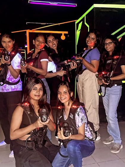 The laser queens have conquered the arena. A group of girls poses confidently with their laser guns after a victorious game.
