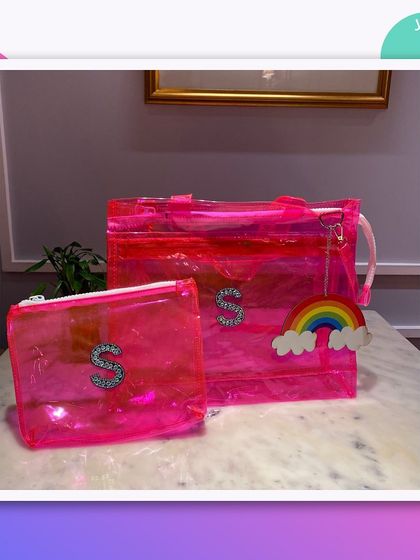 A pink jelly tote bag and matching pouch, personalised with a sparkly 'S' initial and a rainbow charm.