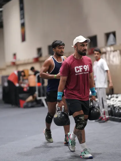 A farmer's carry with heavy kettlebells during a competition. This is a simple but brutal test of grip strength, core stability, and pure grit.