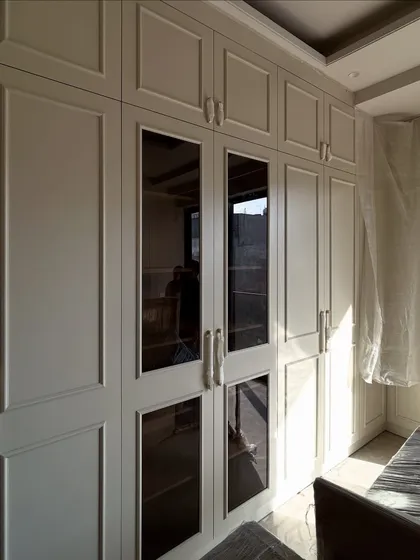 A view of the floor-to-ceiling wardrobes with a mix of solid and glass-paneled doors, providing both concealed and visible storage.